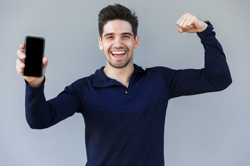 Wall Mural - Cheerful young man showing blank screen mobile phone