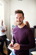 © Flamingo Images - Smiling young designer using his cellphone after an office meeti