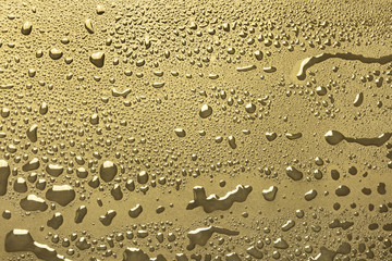 Shiny water drops on golden metal surface, background