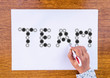 woman hand draws word Team made from Gears on paper sheet