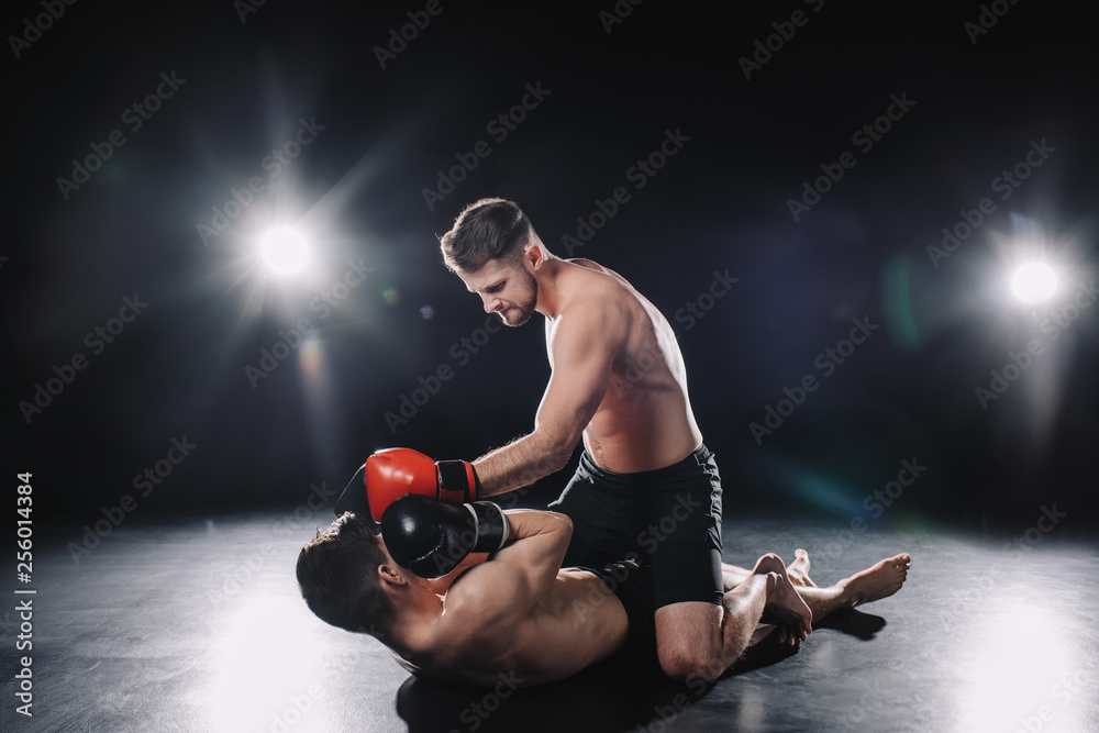 strong mma fighter in boxing gloves sitting on opponent and punching ...
