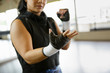 © Natalie Faye - Woman boxer looks at hand wraps in gym