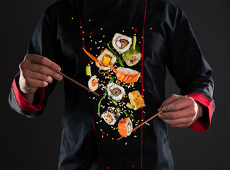 Master chef holding chopsticks with flying sushi