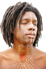 Portrait of young african man with closed eyes and traditional face paint shot at a three quarters angle