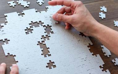 Wall Mural - Hands holding a piece of the puzzle and solve the puzzle. Question mark from pieces of a puzzle.