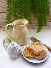 Wall Mural - vertical photo of fritters pancakes with oak flakes on shabby wooden white background with rustic jug