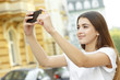 © Nestor - Photo time! Horizontal shot of a young female taking pictures of the city with her smartphone