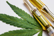 Cannabis Oil Extract In Vape Pen Cartridges Up Close On Cannabis Leaf Against White