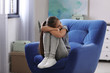 © New Africa - Depressed preteen girl sitting in armchair at home