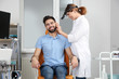 Professional otolaryngologist examining man in clinic. Hearing disorder