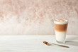 Glass of caramel macchiato on table against color background. Space for text