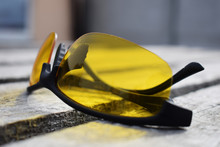 Safety Yellow Glasses On A Wooden Background. Glasses Lie.