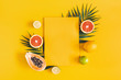 Summer composition. Tropical palm leaves, fruits, yellow paper blank on yellow background. Summer concept. Flat lay, top view, copy space