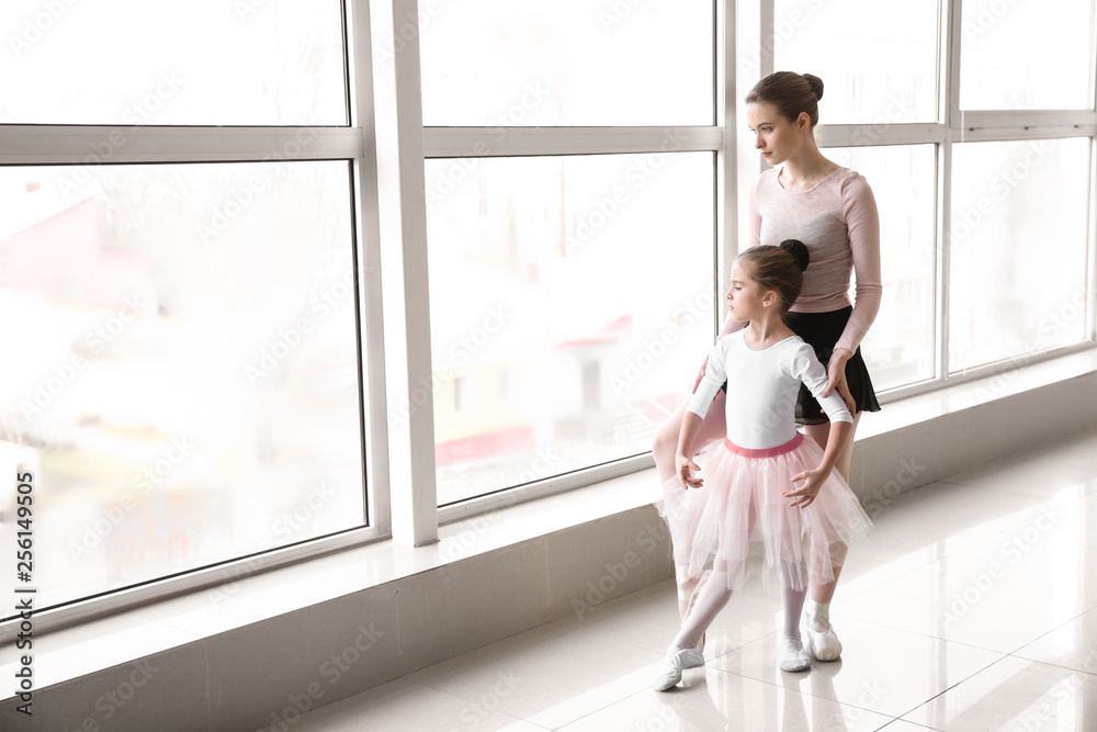 Little ballerina training with coach in dance studio