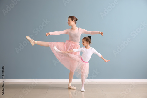 Foto  Little ballerina with coach against color wall