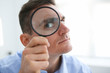 Man in office work holding magnifying glass in hand