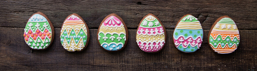 gingerbread cookie in the form of color easter eggs on dark wooden background.