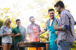 © NDABCREATIVITY - Happy friends enjoying barbecue party in forest