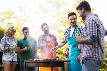 Wall Mural - Happy friends enjoying barbecue party in forest