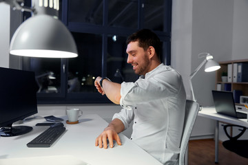 Canvas Print - business, technology and ai concept - happy businessman using voice command recorder on smiling watch at nigh office