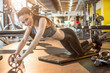 © Bojan - Attractive woman with slim stomach doing abdominal exercises with wheel roller at gym.