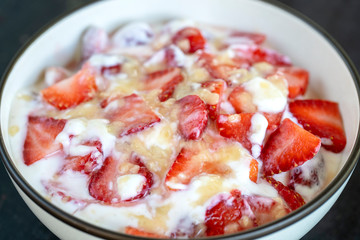 Red strawberry and white yogurt brulee. Fruit dessert on breakfast with wedges of perfectly ripe in season strawberry, closeup