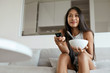 Woman watching television, having breakfast at home in morning
