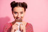 Close-up portrait of her she nice-looking cute charming attractive lovely glamorous cheerful girl in striped t-shirt biting tasting eating desirable favorite cocoa dessert isolated on pink background