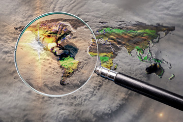 Collage with magnifying glass searching at the earth map with huge hurricane, and hurricane eye above the America. Elements of this image furnished by NASA.