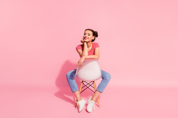 Nice-looking attractive glamorous magnificent lovely shine cheerful cheery girl wearing striped tshirt jeans sitting on chair having free time isolated over pink pastel background
