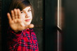 © Iryna - Portrait thoughtful caucasian teenager with long straight hairstyle showing stop sign with palm, looking at camera in dark modern loft interior. Child wthout parents, independent concept.