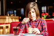 © Iryna - Portrait of teenager boy drinking tea with dessert having breakfast in cafe.