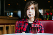 © Iryna - Close up portrait of teenager boy drinking tea sitting on red couch having breakfast in cafe interior.