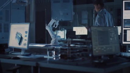 Leinwandbilder - Professional Heavy Industry Robotics Engineer Wearing White Coat Holding Tablet Computer Walks Through Laboratory. Facility Full of Computers, Various Industrial Design Components and with Robotic Arm