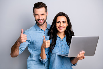 Close up photo of satisfied cheerful enjoying students fellows  isolated recommending advising products sites holding electronic device feeling positive wearing denim jackets on grey background 
