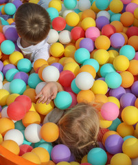 Wall Mural - Boy and girl playing in colorful balls on attraction