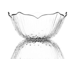 A single empty glass dessert bowl isolated on a white background with reflection. High contrast black and white, black line lighting.