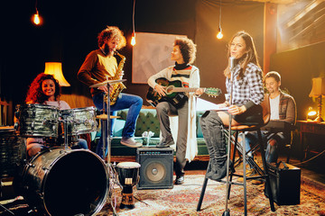 Canvas Print - Band practice in home studio. Woman singing while rest of the band playing instruments.