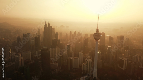 Obraz na płótnie Menara Kuala Lumpur Tower ze słońcem. Widok z lotu ptaka centrum Kuala Lumpur, Malezja. Dzielnica finansowa i centra biznesowe w azjatyckim mieście miejskim. Wieżowiec i wieżowce o zachodzie słońca.