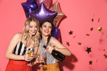 Poster - Photo of two young women 20s in stylish outfit holding festive balloons and drinking champagne on party