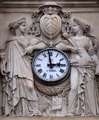 Two muses support the clock, topped by the coat of arms of Cardinal Richelieu, facade of the Saint Ursule chapel of the Sorbonne in Paris, France 