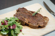 © Alexander - A piece of fried meat and greens on a wooden cutting board on the table
