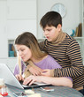 © JackF - Young woman working at laptop with small son indoors