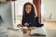 © Flamingo Images - Smiling businesswoman sitting at her office workstation going ov