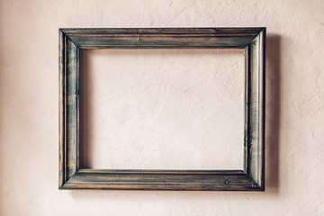 Old wooden frame on a rustic plastered wall