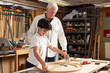 © Cavan Images - Carpenter looking at boy measuring wooden ring in workshop