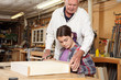 © Cavan Images - Carpenter assisting girl in making wooden shelf