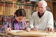 © Cavan Images - Carpenter teaching girl in workshop