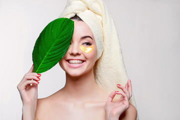 portrait of young beautiful woman with healthy glow perfect smooth skin holds green tropical leaf. g