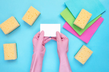 Cleaning concept A set of cleaning tools, rags, sponges, brushes, hands in rubber gloves on a light blue background, top view, flat lay, close-up